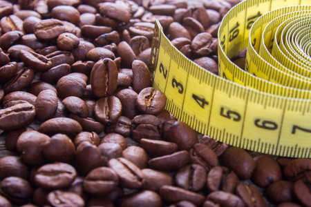 coffee beans and yellow measuring tape on an old wooden tableの写真素材