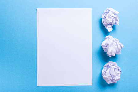 Crumpled paper ball and clean sheet on a blue backgroundの写真素材