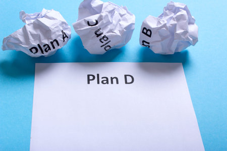 Crumpled paper Plan A B C and clean sheet Plan D on a blue backgroundの写真素材