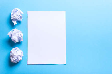 Crumpled paper ball and clean sheet on a blue backgroundの写真素材