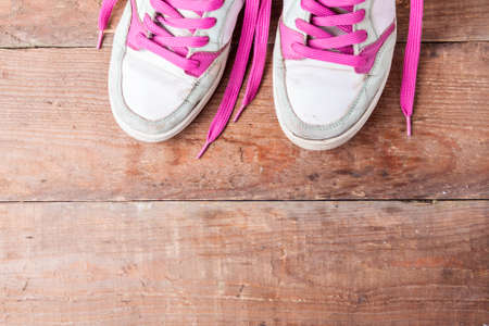 Old women's sneakers with pink laces on old boards. How to choose new sneakers? Copy space for textの写真素材