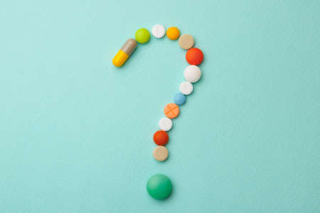 Symbol question mark from colored tablets and capsules on  green background. What medicines to choose better, what will helpの写真素材