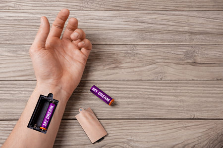 Dream gives strength and energy moves on. Word my dream is written on the battery. Hand of man with...