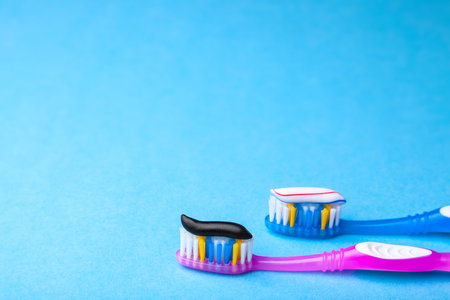 Whitening toothpaste is usual colored and black from charcoal on toothbrush. Concept. Which...