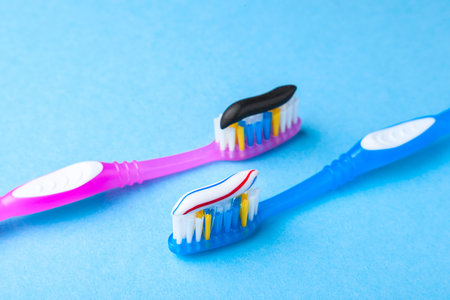 Whitening toothpaste is usual colored and black from charcoal on toothbrush. Concept. Which toothpaste to choose? How to whiten your teeth?の写真素材