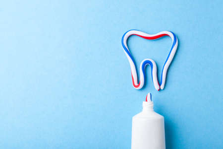 Tooth-paste in the form of tooth. Tube of the paste on blue background. Refreshing and whitening toothpaste. Copy space for textの写真素材