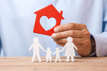 The concept of renting a home, credit or insurance. Man in  shirt is holding  house and  family is standing next to himの写真素材