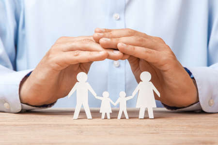 Medical or travel insurance. Man covers the family with his hands from his father, mother, son and daughterの写真素材