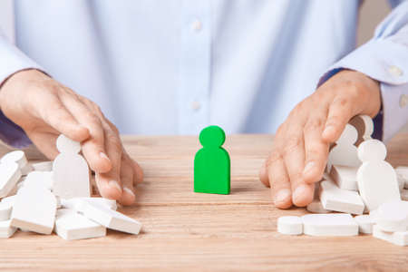 Choosing good leader worker from the crowd of bad. HR. Man in shirt with his hands slips the little men and singles out one.の写真素材