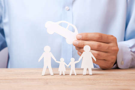 The concept of car rental, credit or insurance. Man in  shirt is holding  car in his hand and next to his familyの写真素材