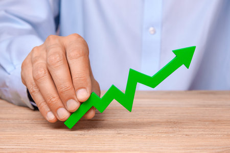 Growth in sales and profits. Green arrow pointing up in the hands of man