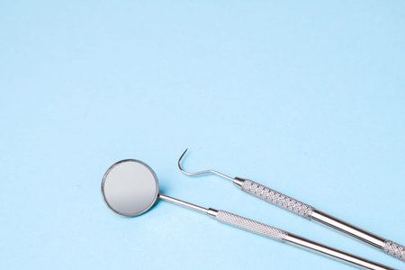 Dental instruments. Dental mirror and probe hook on blue background. Copy space for text