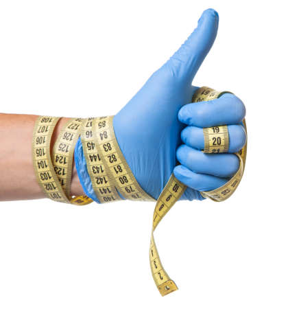 Concept of excess weight, weight loss, liposuction. Doctor in blue glove and measuring tape in his hands is isolated on white backgroundの写真素材