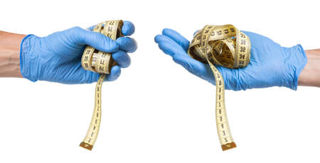 Concept of excess weight, weight loss, liposuction. Doctor in blue glove and measuring tape in his hands is isolated on white backgroundの写真素材