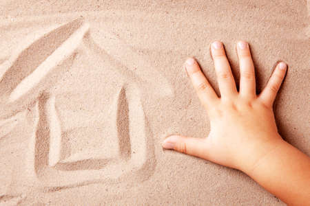 The house is painted on sand by the hand of child. Concept House by the seaの写真素材