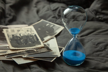 Stack old photos and hourglass on table. Postcard rumpled and dirty vintage. Retro card