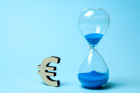Hourglass and symbol of money euro on blue background.