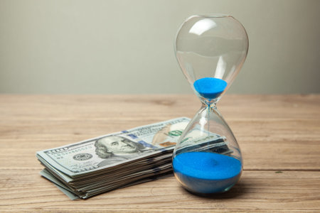 Hourglass and stack of money dollars of banknotes.