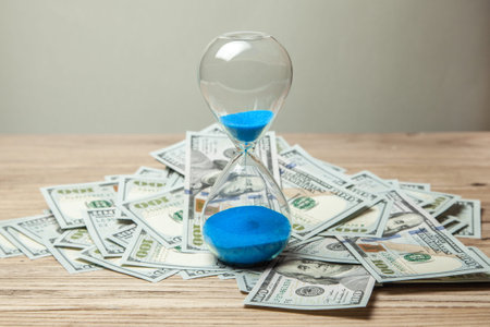 Hourglass and bunch of money dollars of banknotes. Time is money