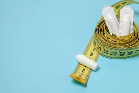 Suppository for anal or vaginal use and yellow measuring tape. Candles for the treatment of obesity, extra weight, for weight loss. Copy space for textの写真素材