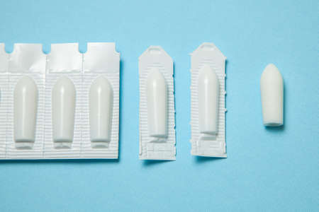 Suppository for anal or vaginal use on a blue background. Candles for treatment of hemorrhoids, temperature, thrush, inflammationの写真素材