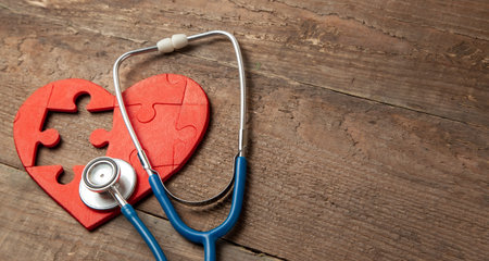 Heart puzzle red and stethoscope on wooden background. Concept diagnosis and treatment of heart disease, medical insurance. Copy space for textの写真素材