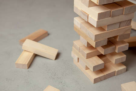 Tower of wooden blocks on gray background. Board game for the whole family or party. Concept of building business or building team.の写真素材