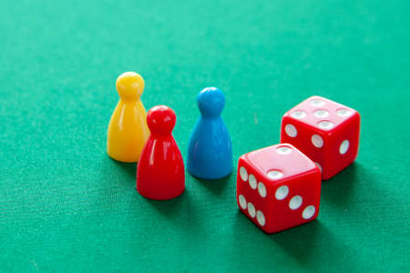 Colored game figures chips for board games. Collection of dice cubes on green tableの写真素材