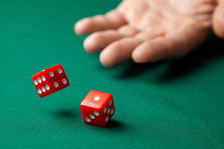 Man holds two red dices and throws them on green poker gaming table in casino. Concept of online...