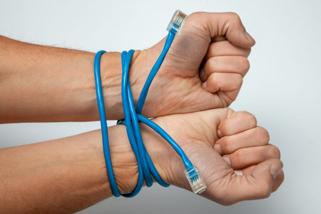 Online work, dependence on the Internet. Male hands wrapped with twisted pair blue cable on gray...