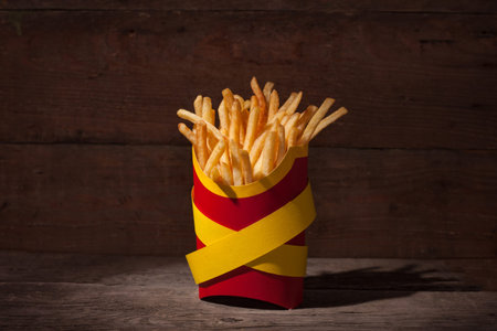 French fries in a red packing box on wooden table with yellow police ribbons