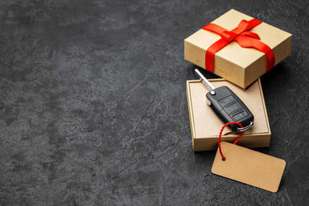 Gift box with car keys with remote control alarm system with red ribbon bow and label. Copy space for textの写真素材