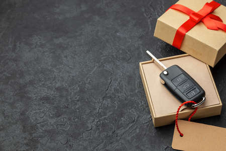 Gift box with car keys with remote control alarm system with red ribbon bow and label. Copy space for textの写真素材
