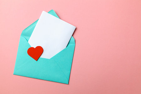 Love letter. Message of declaration of love. Green envelope with hearts and blank letter on pink background. mock-upの写真素材