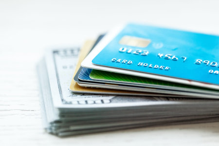 Credit card and stack of cash dollars on white background