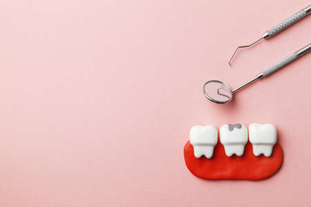 Healthy white teeth and tooth with caries on pink background  and dentist tools mirror, hook. Copy space for textの写真素材