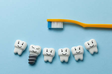 Healthy white teeth and implants are smiling on blue background with toothbrush.の写真素材