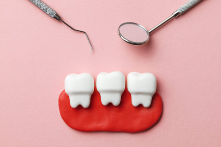 Healthy white teeth on pink background and dentist tools mirror, hook