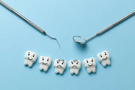 White tooth with caries on blue background  and dentist tools mirror, hookの写真素材