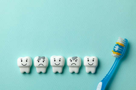 Healthy white teeth are smiling and tooth with caries is sad on green mint background and Toothbrushの写真素材