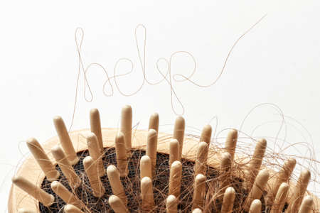 Hair loss. Comb with hair and inscriptions HELP. Concept of how to help and strengthen hair from falling out.の写真素材