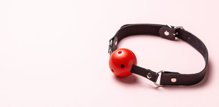 Red Ball gag on pink background. Intimate toys. Sex abuse slavery. Copy space for textの写真素材