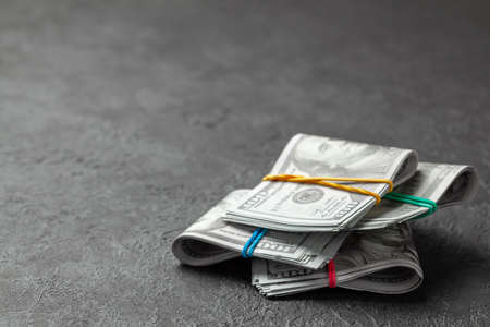 Stacks of cash dollars tied with colored office bands on dark background. Concept of savings or bribe. Copy space for textの写真素材