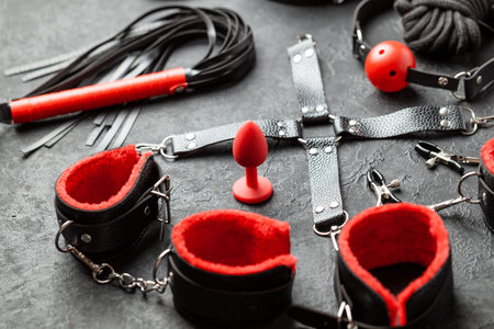 Set of erotic toys for BDSM. The game of sexual slavery with handcuffs, whip, gag and leather...