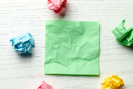 Colored wrinkled note paper on white wooden tableの写真素材