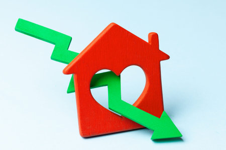 Arrow down and house on blue background. Falling market price of real estate.