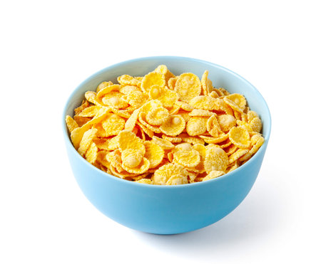 Dry breakfast cornflakes. Blue plate full of cereal. Isolated on white background