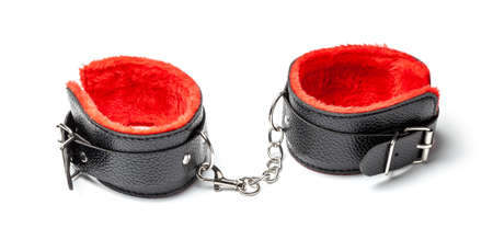 Bondage, BDSM black leather handcuffs with red fur inside, on  chain. Sex toys. Isolated on white backgroundの写真素材