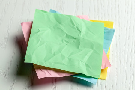 Colored wrinkled note paper on white wooden table