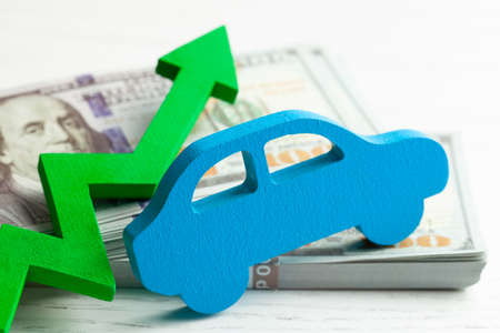 Green arrow graphic up on the background of the car and a stack of money cash dollars. The concept of the growth of the car market, insurance, price growth, repair costsの写真素材